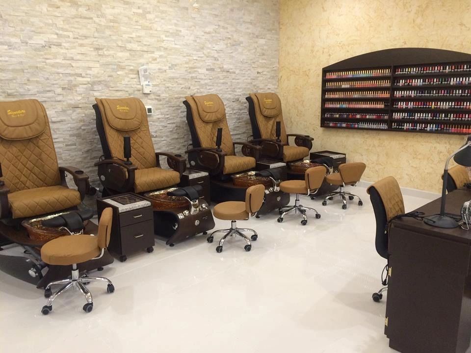 A nail salon pedicure row lit by recessed cans, beside a wall-mounted polish display.