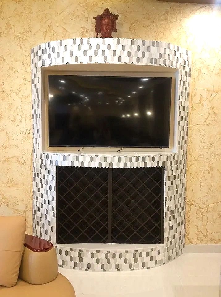 A tiled feature wall with a recessed, wall-mounted television above a built-in wine rack.