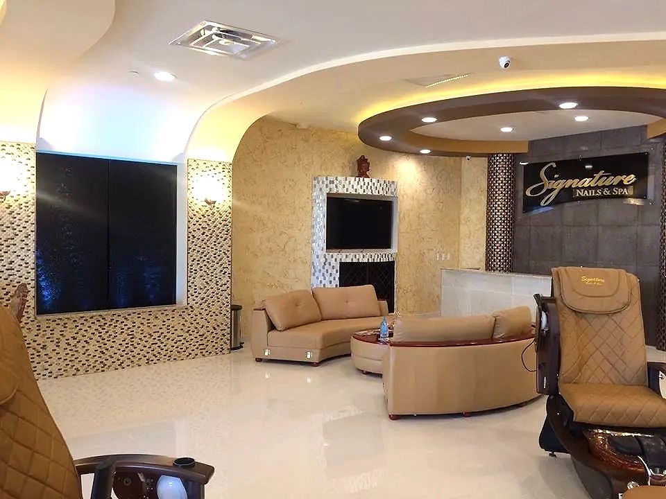 Salon lobby with a cove-lit ceiling, wall sconces and recessed downlights over the seating area.