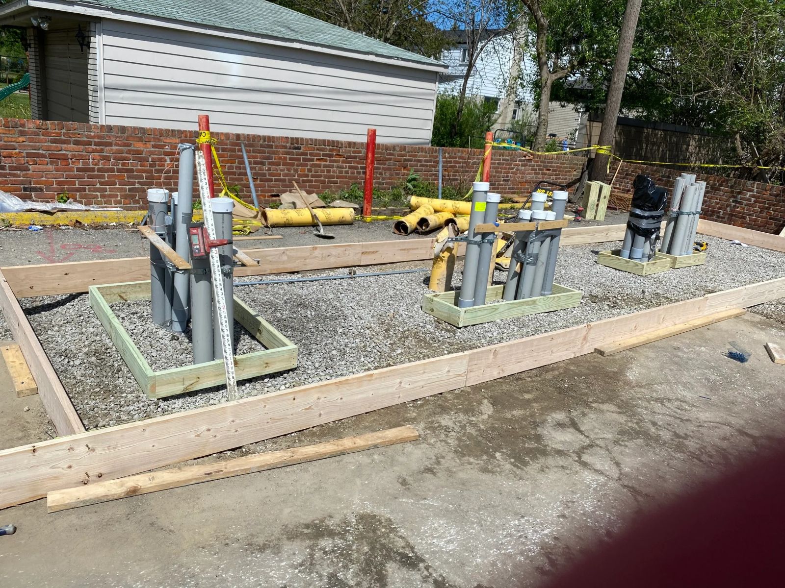 Formed footings on a gravel base with capped conduit stub-ups bundled and braced ahead of the pour.